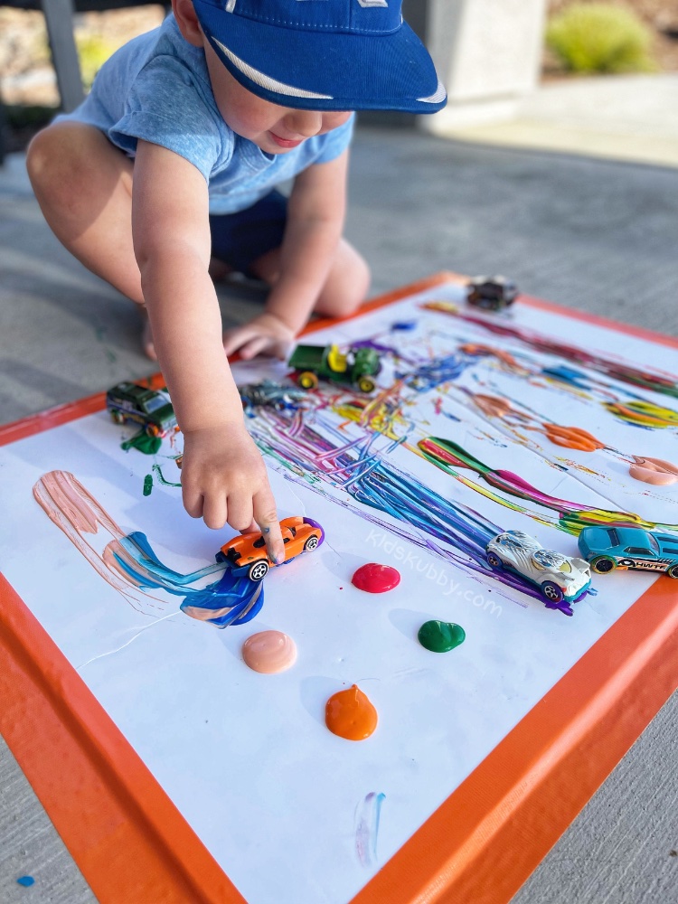 Your kids are going to love painting with cars. It is so easy with very little supplies you most likely already have at home-washable paint, toy cars, and paper. Let your child create their own little art piece by driving the cars through the paint.