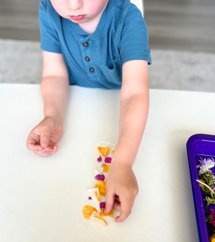 How to make awesome bracelets for kids using packing tape and flowers from a nature walk! A fun and easy craft idea for kids of all ages. My preschoolers had a blast making this project with me. Perfect for the spring and summer months!